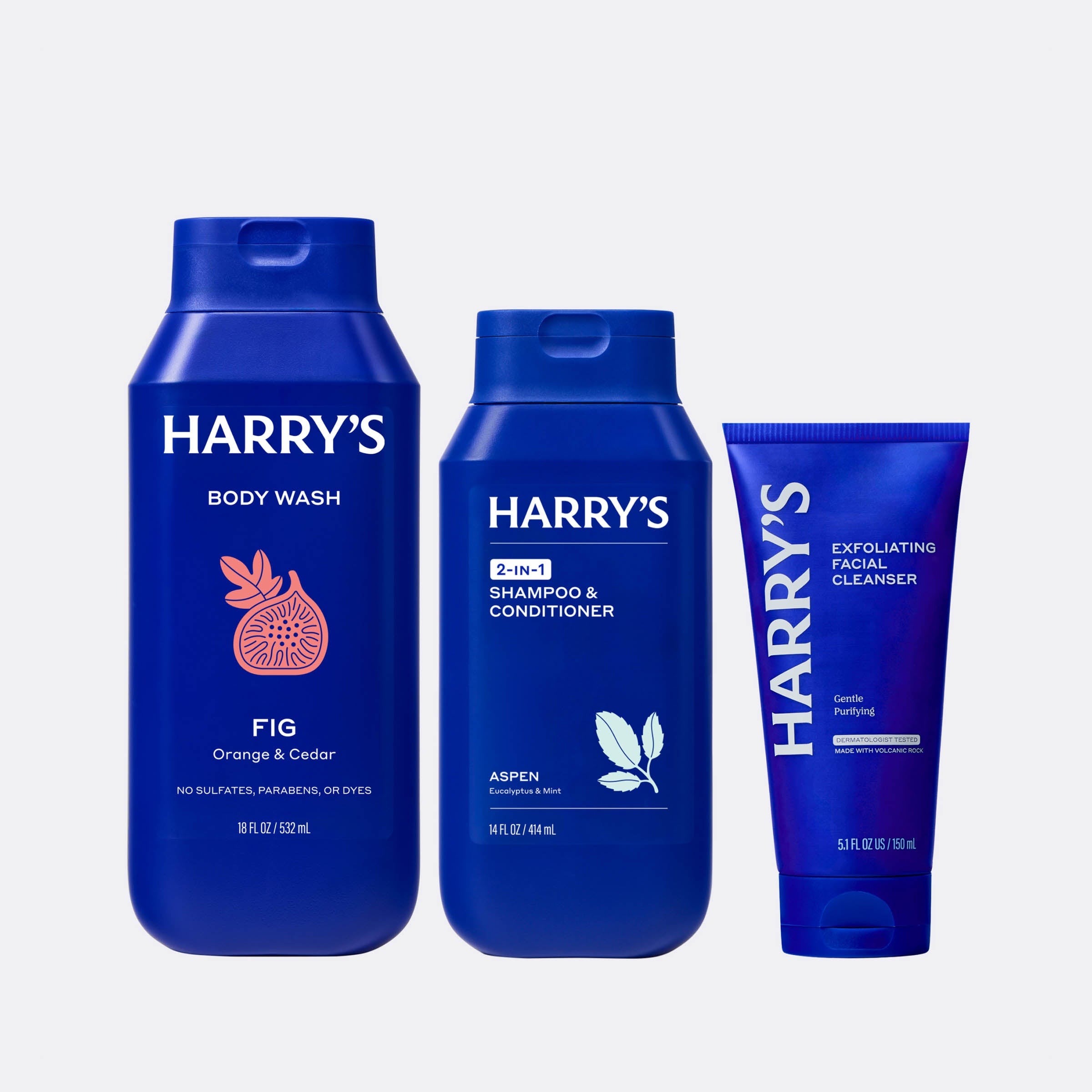Three blue bottles of Harry's grooming products on a light gray background