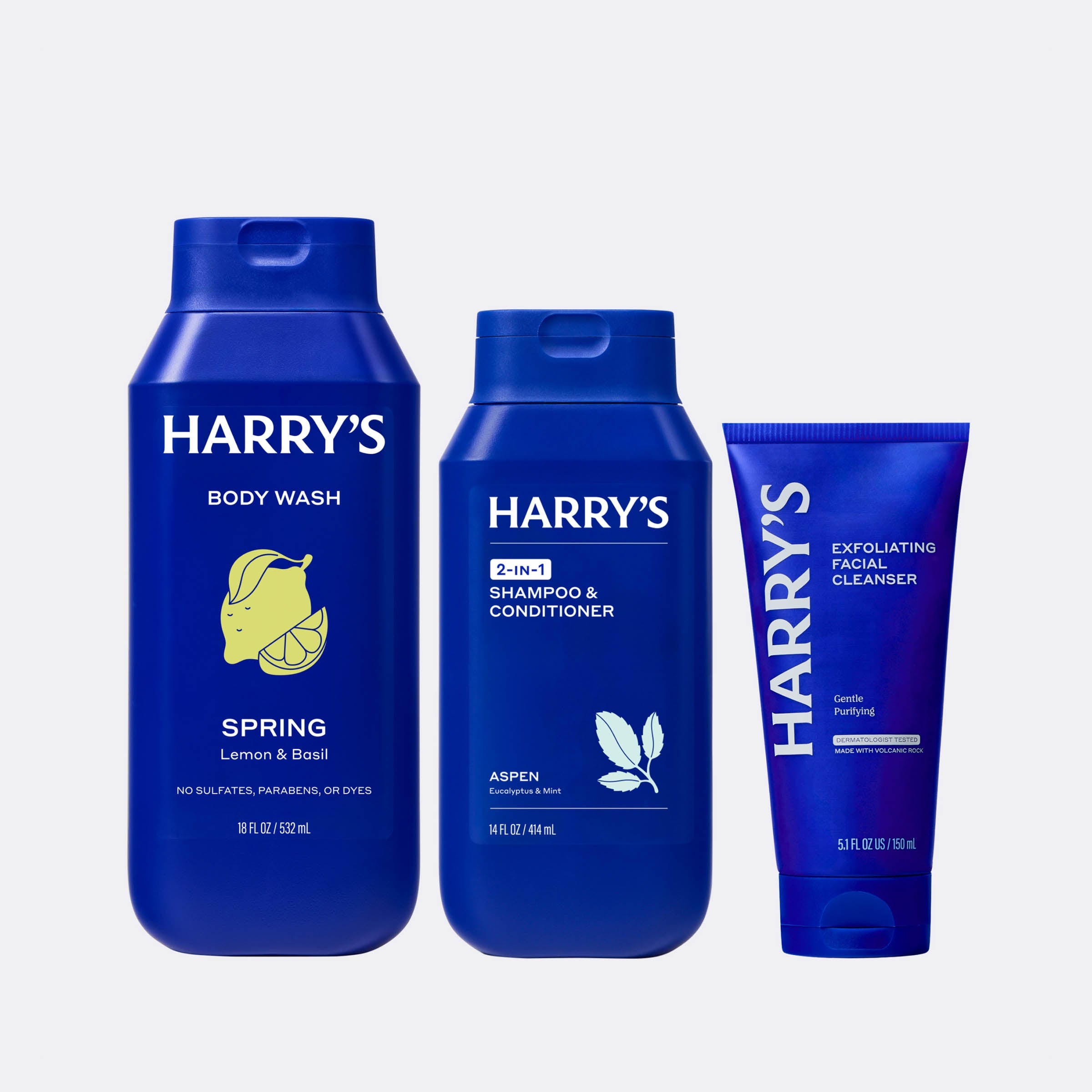 Three blue bottles of Harry's grooming products on a light gray background